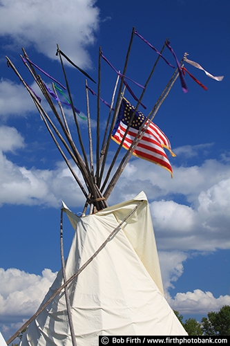 Native Americans;cultural;culture;authentic design;teepee;a cone shaped tent;a Native American tent;a portable structure;teepees;tepee;tipi;traditionally made of animal skins upon wooden poles;tradition;customs;Native American Indians customs;traditional;smoke flaps at the top of structure;tee pee with a flag;teepee with an American flag