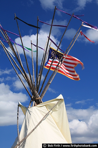 Native Americans;cultural;culture;authentic design;teepee;a cone shaped tent;a Native American tent;a portable structure;teepees;tepee;tipi;traditionally made of animal skins upon wooden poles;tradition;customs;Native American Indians customs;traditional;smoke flaps at the top of structure;tee pee with a flag;teepee with an American flag