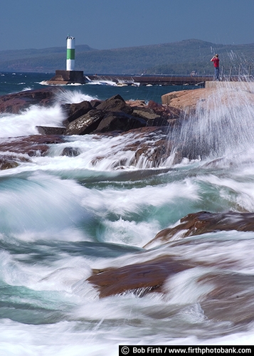 Grand Marais Lighthouse;biggest fresh water lake;crashing waves;destination;Great Lakes;Lake Superior;Minnesota;MN;North Shore;Sawtooth Mountains;shoreline;summer;teenager;tourism;tourist;young adult;man standing on rock