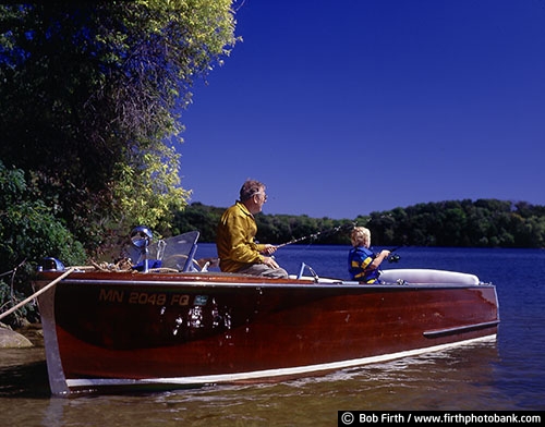 boy;child;Chris Craft;elder;elderly;fisherman;fishing;grandpa;grandson;kid;Lake Minnetonka;man;Minnesota;MN;motorboat;old man;retired;retiree;peaceful;senior citizen;summer;water;wood boat;companionship;generations;grandfather;fishing pole;fun pastime;recreational